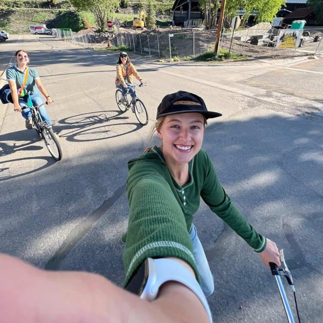 Photo of Emily with two friends biking in town.