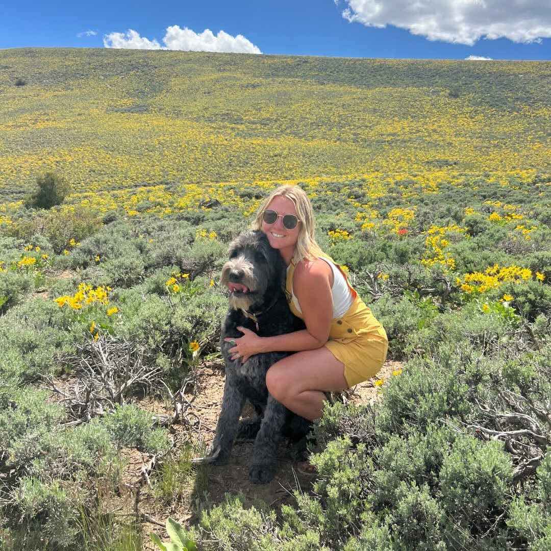 Jessica smiling with her dog Steve on a hike.