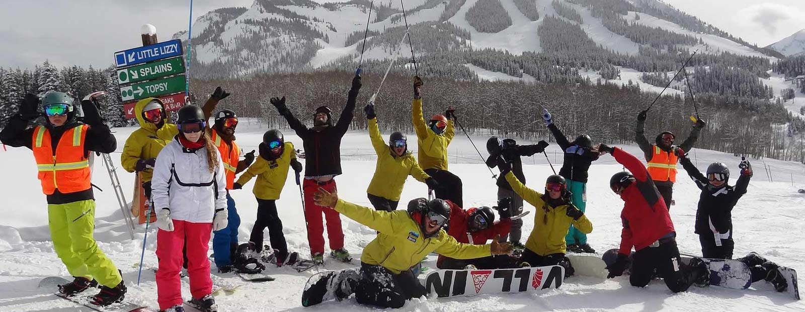 Group of skiers and snowboarders in front of a mountain 